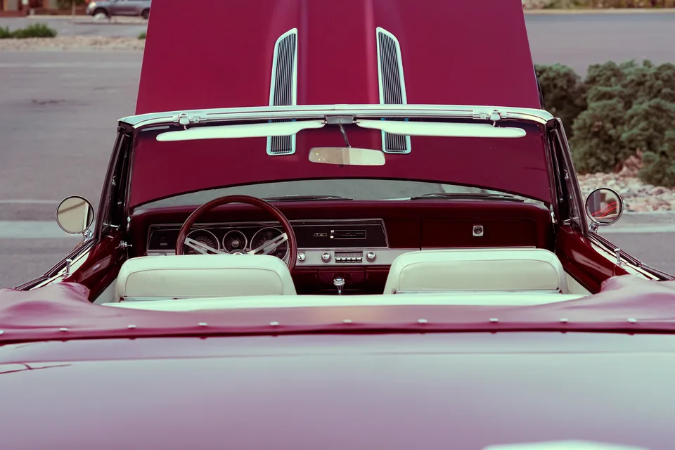 The rear deck and white interior of a burgundy vintage convertible