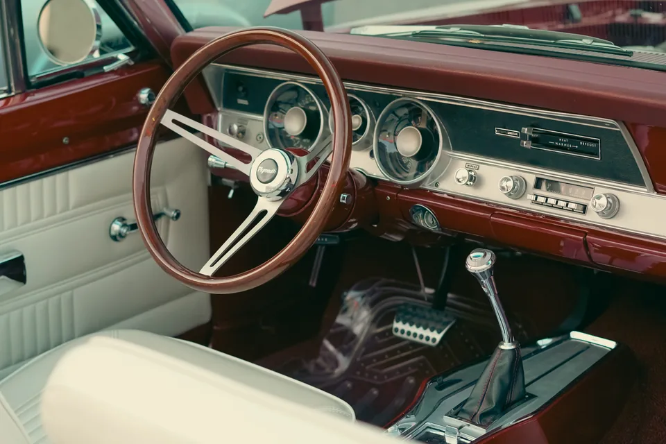 Chrome steering wheel and warm dashboard details inside a classic car