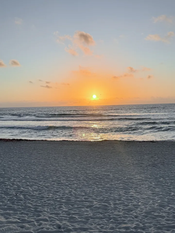 The sun setting over the ocean and an empty beach
