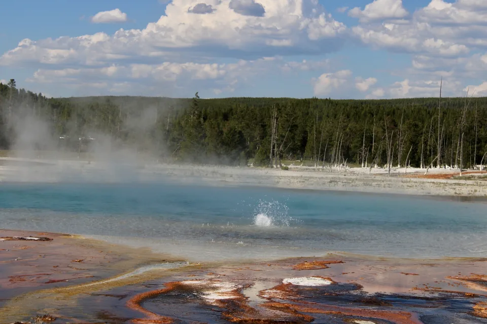 A pale blue thermal pool rimmed with rust-colored mineral